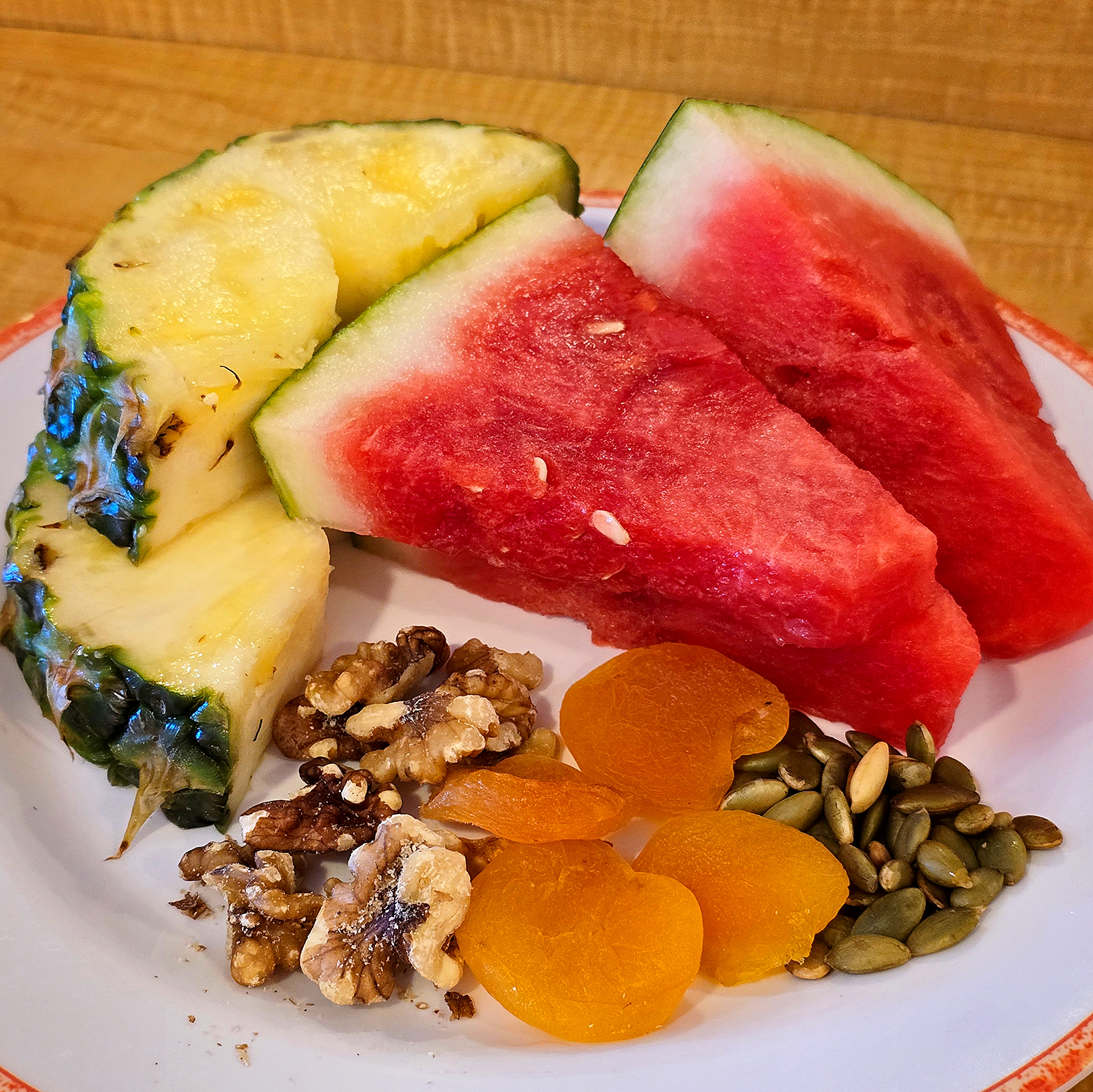 plate of watermelon, pineapple, walnuts, dried apricots, and pumpkin seeds