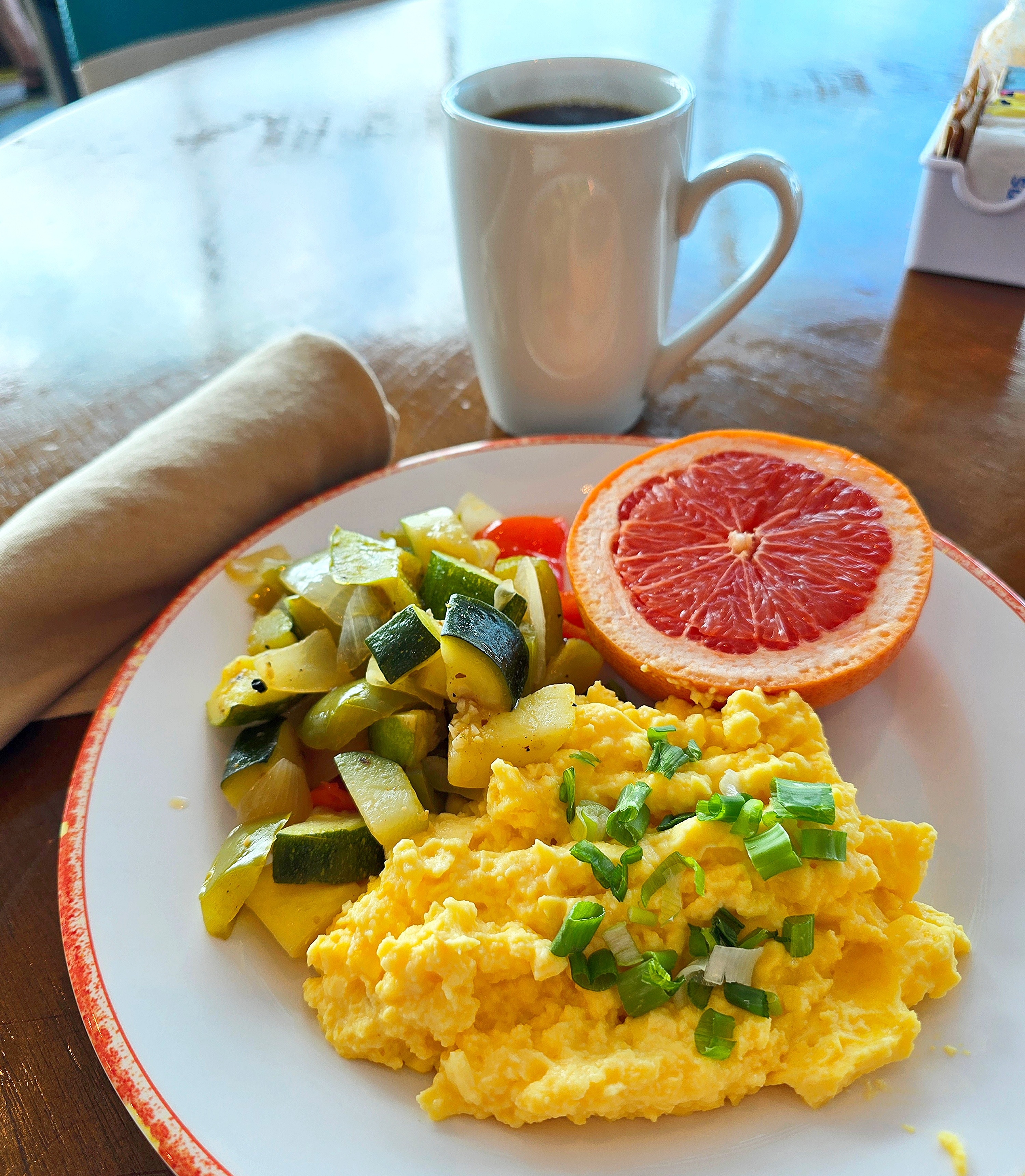 scrambled eggs, sauteed vegetables, and grapefruit